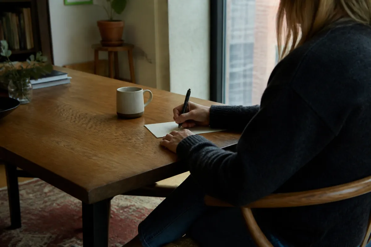 Someone writing a short note at a table.